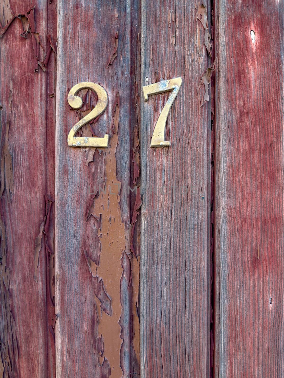Number 27 on red painted old wooden wall. Red background.