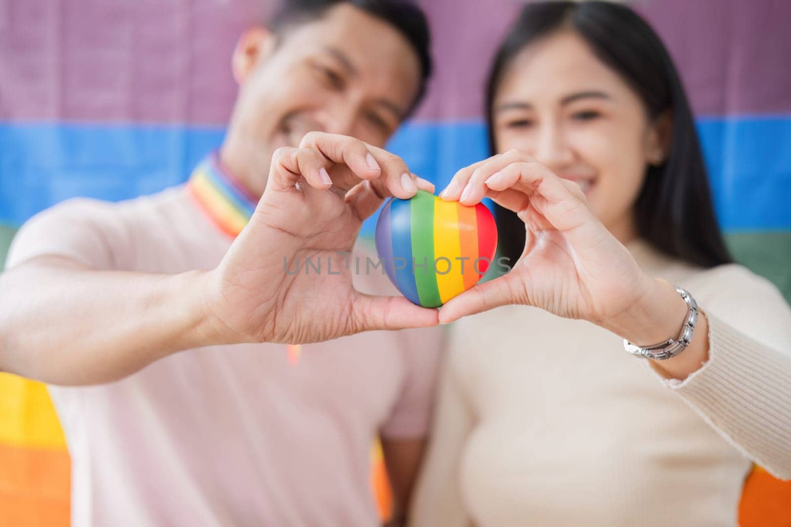 Men and women hold rainbow hearts, a symbol of the LGBT community, in support of gender equality..