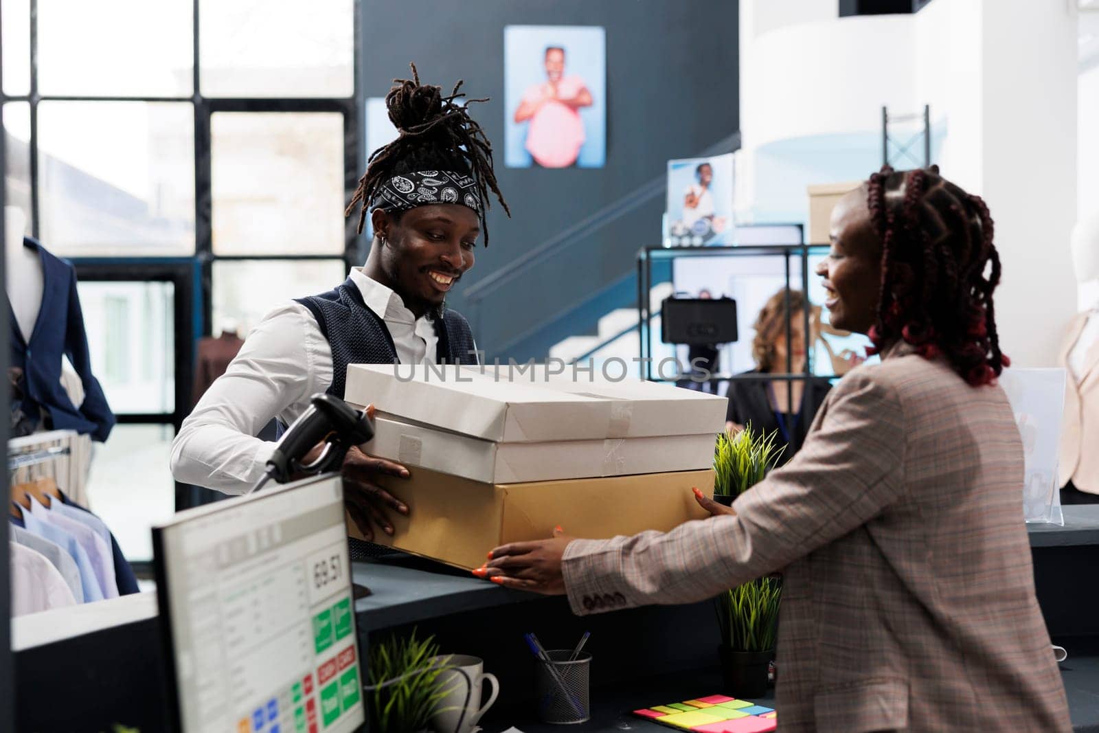 African american shopper holding packages fiiled with fashionable clothes, paying for merchandise at cash register in showroom. Customer buying stylish fashion collection, commercial activity