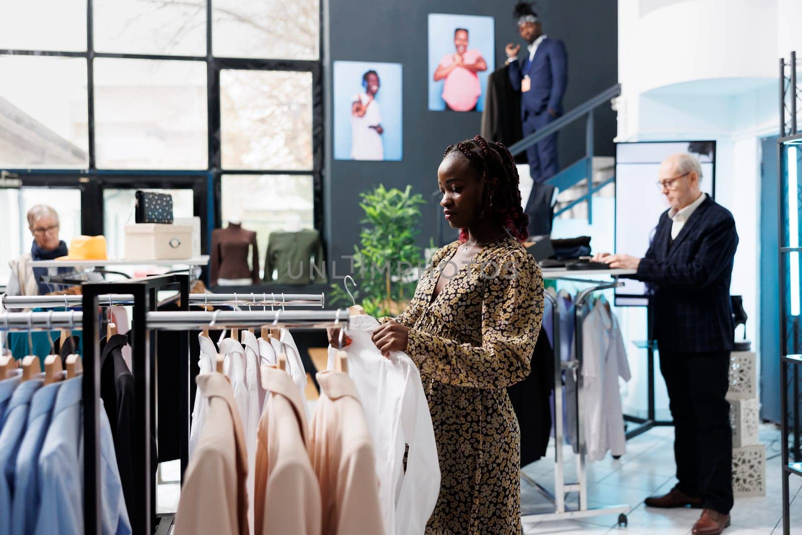 African american client looking at shirt for formal wear, checking fabric in clothing store. Stylish pregnant woman looking at new fashion collection, buying trendy merchandise and accessories