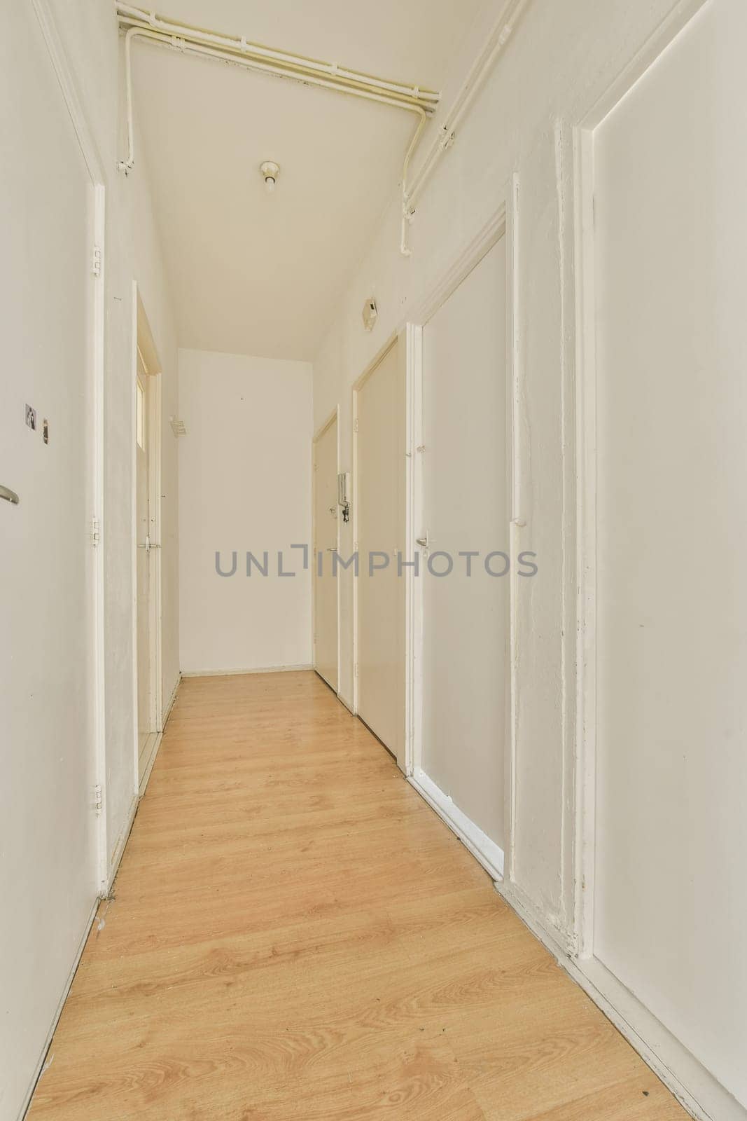 a hallway with wood floors and white walls and doors by casamedia