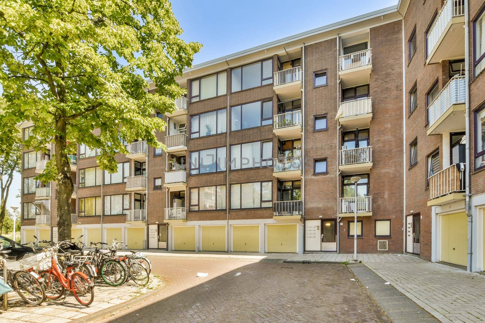 two bicycles parked in front of an apartment building on a sunny day with blue sky and sun shining through the windows