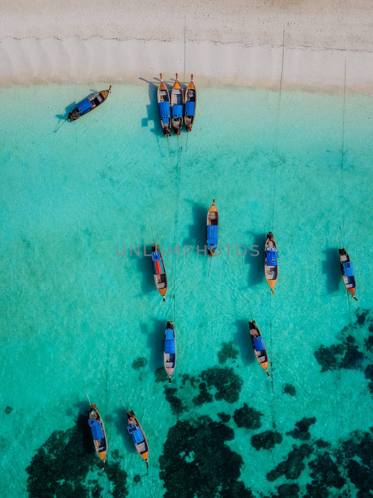 Koh Lipe Island Southern Thailand with turqouse colored ocean and white sandy beach at Ko Lipe. Longtail boats on the beach from above seen from a drone aerial view