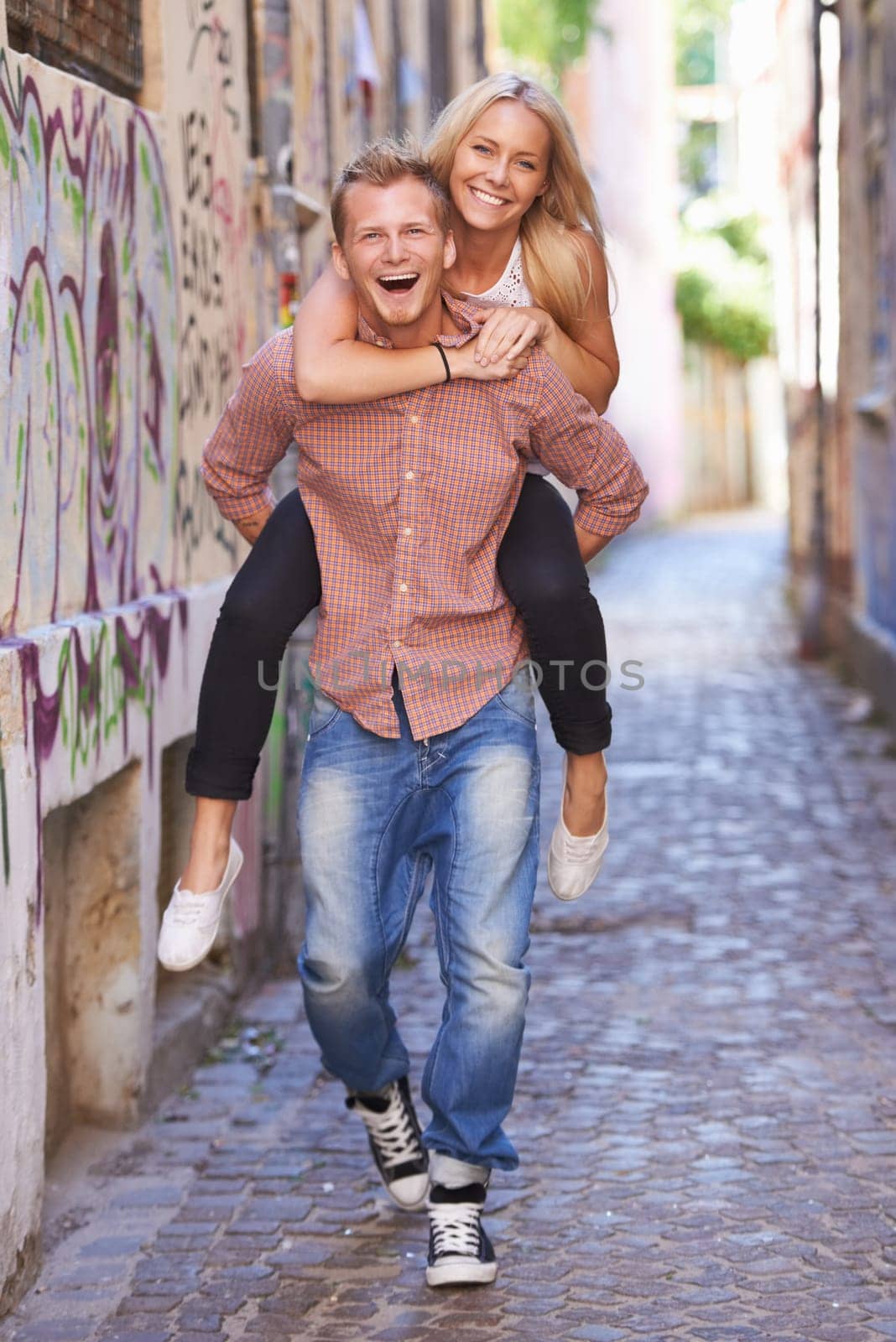 Couple, happy or piggyback on street in city, fun support or romance in committed relationship. Excited man, woman and smile for adventure in amsterdam, travel and care for love together on honeymoon by YuriArcurs