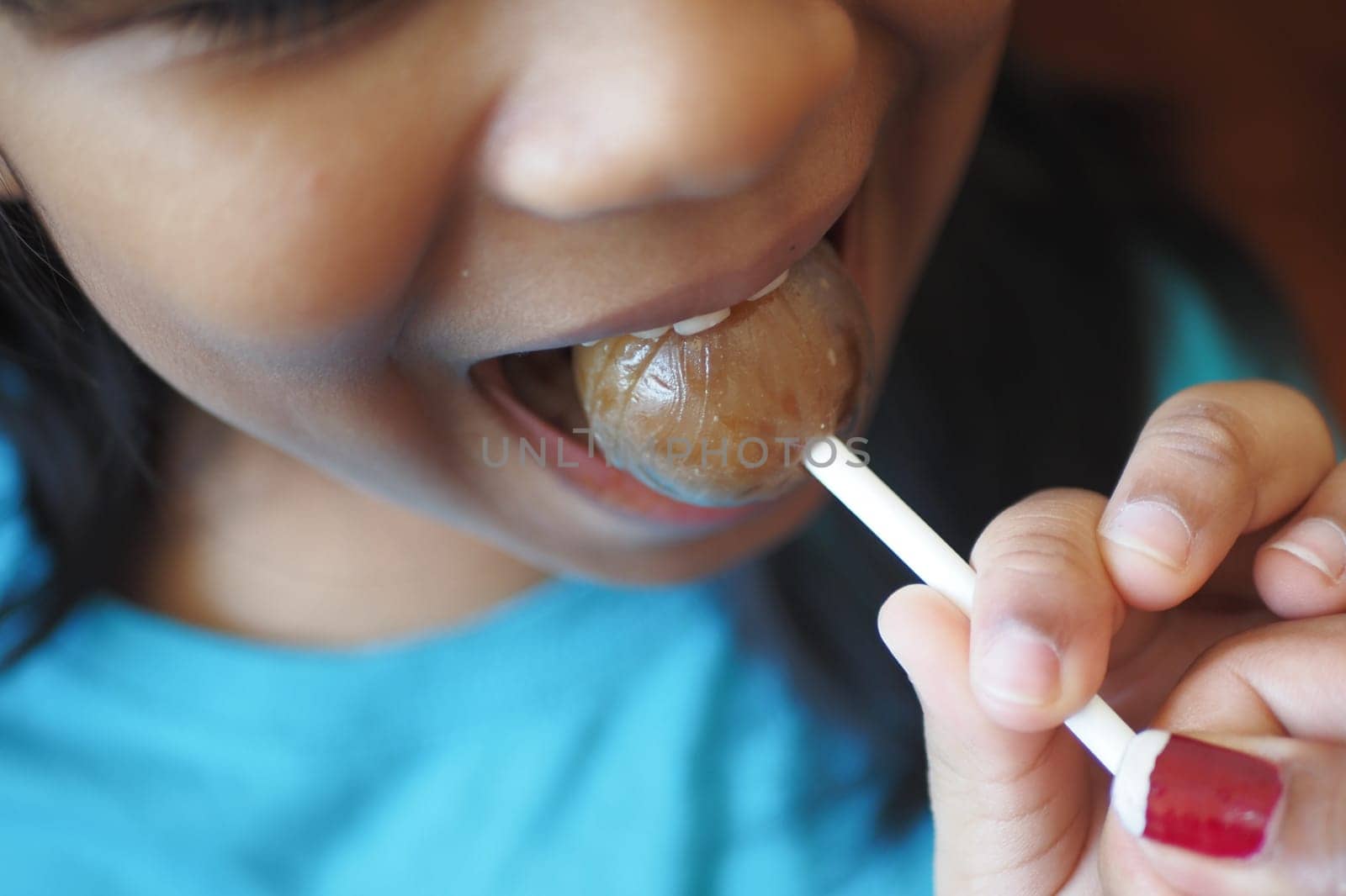 child is licking colorful candy on stick,