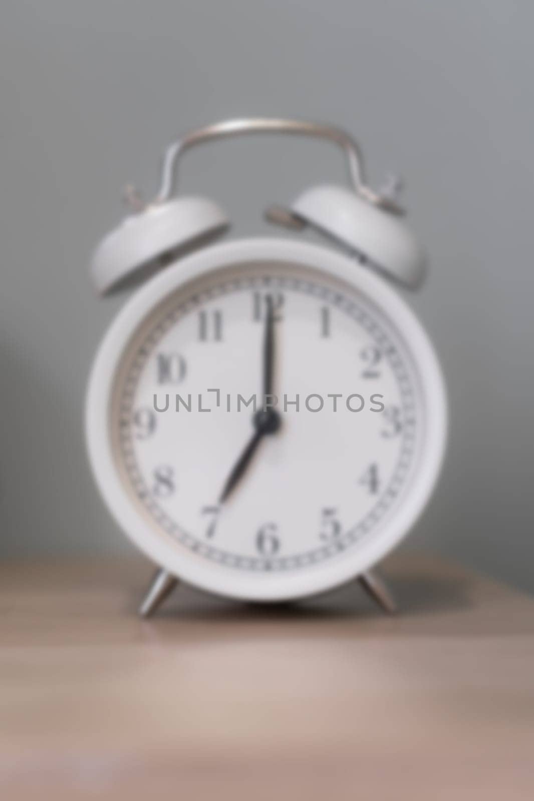 Close-up of a round white alarm clock on a table in the bedroom. by AnatoliiFoto