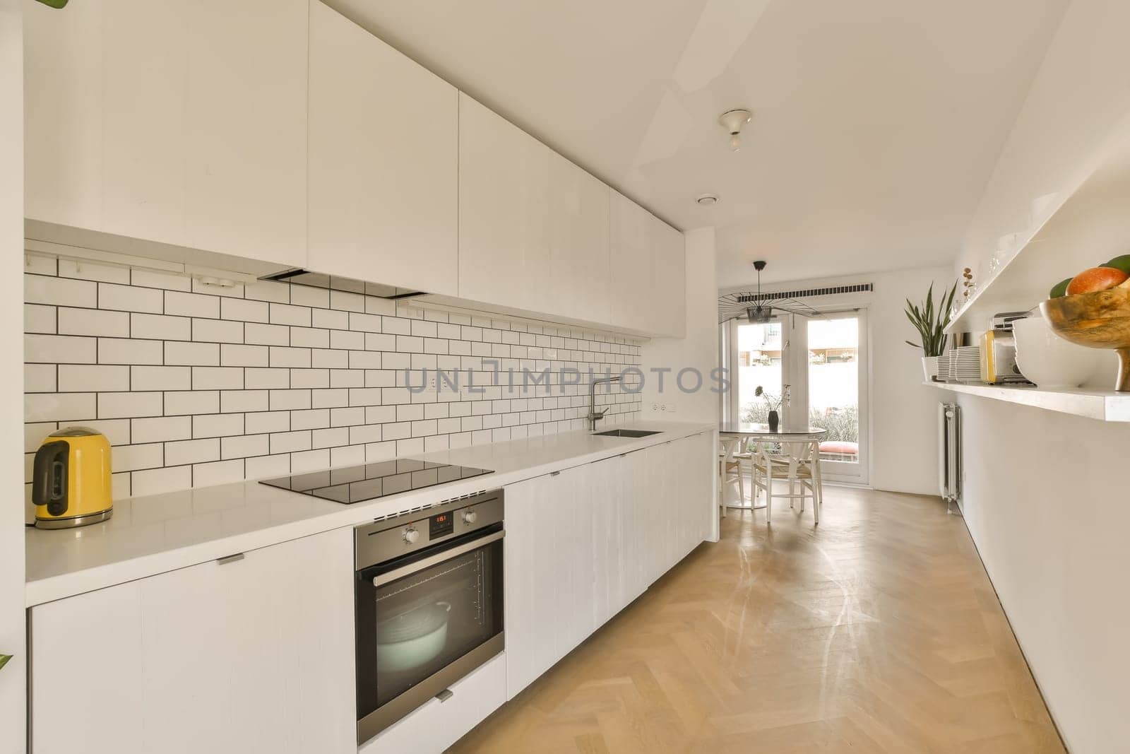 a white kitchen with white cabinets and a wood floor by casamedia