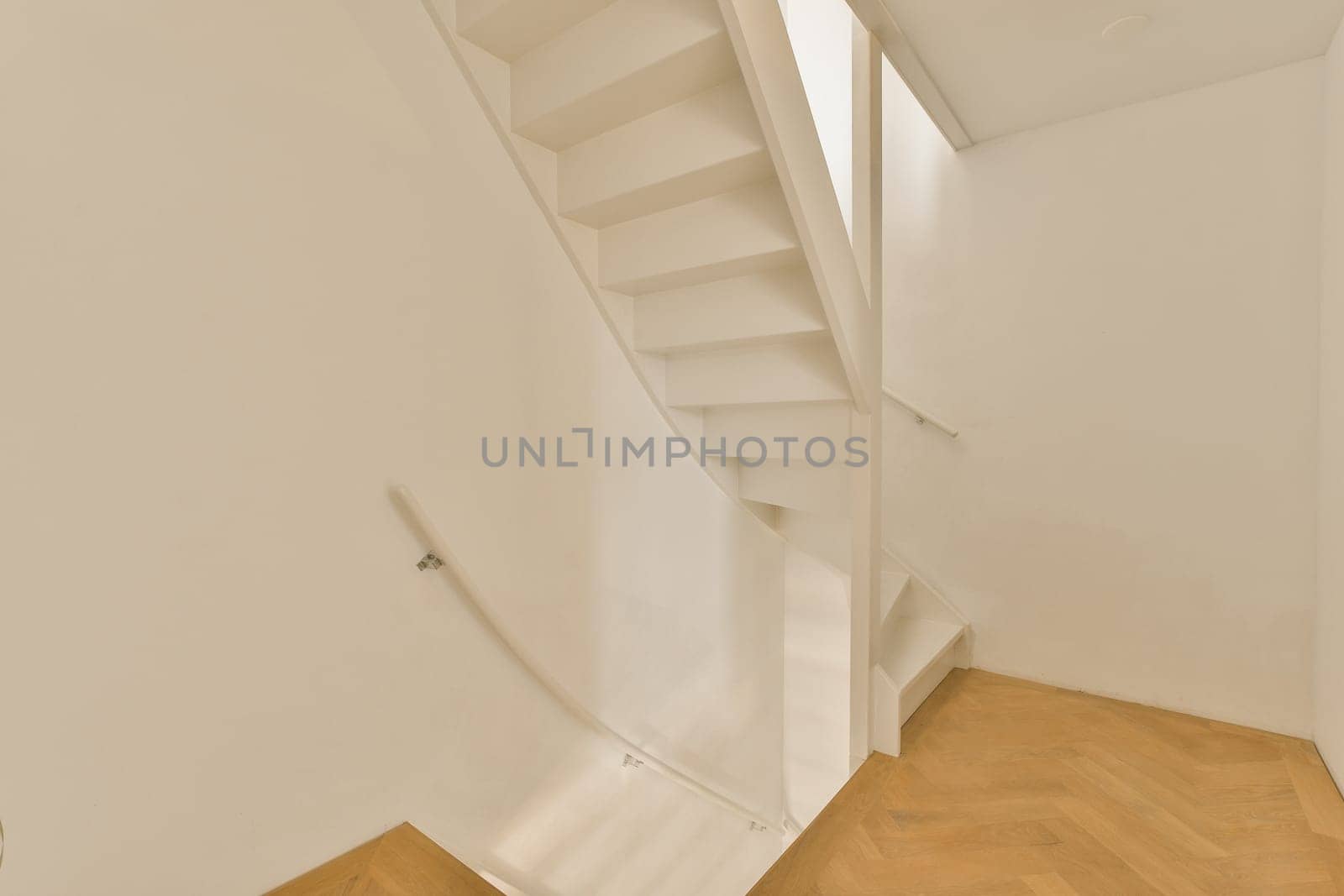 a white room with wood flooring and a staircase leading up to the second floor, which is also empty