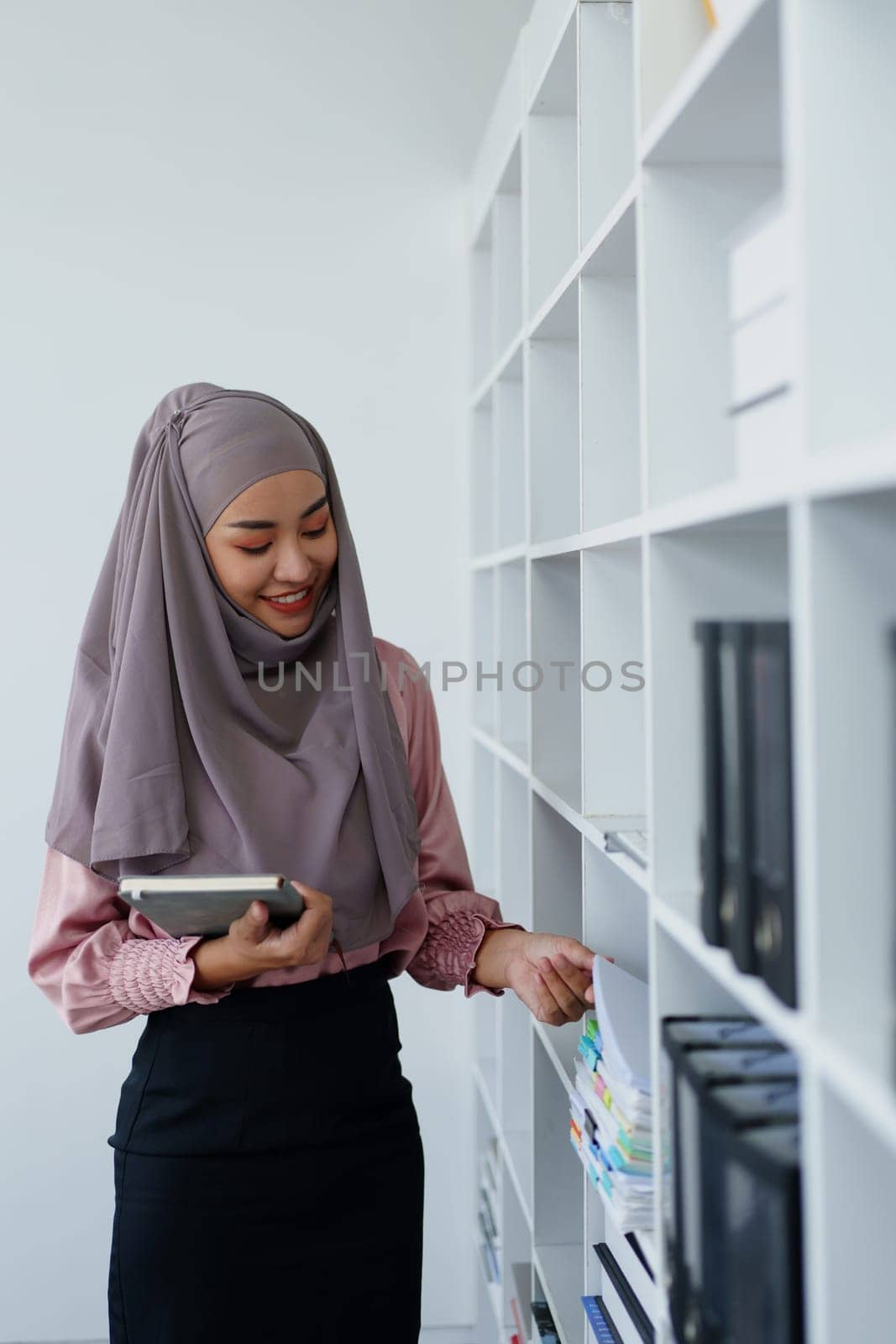 Muslim female employee Searching for documents in the office. by Manastrong