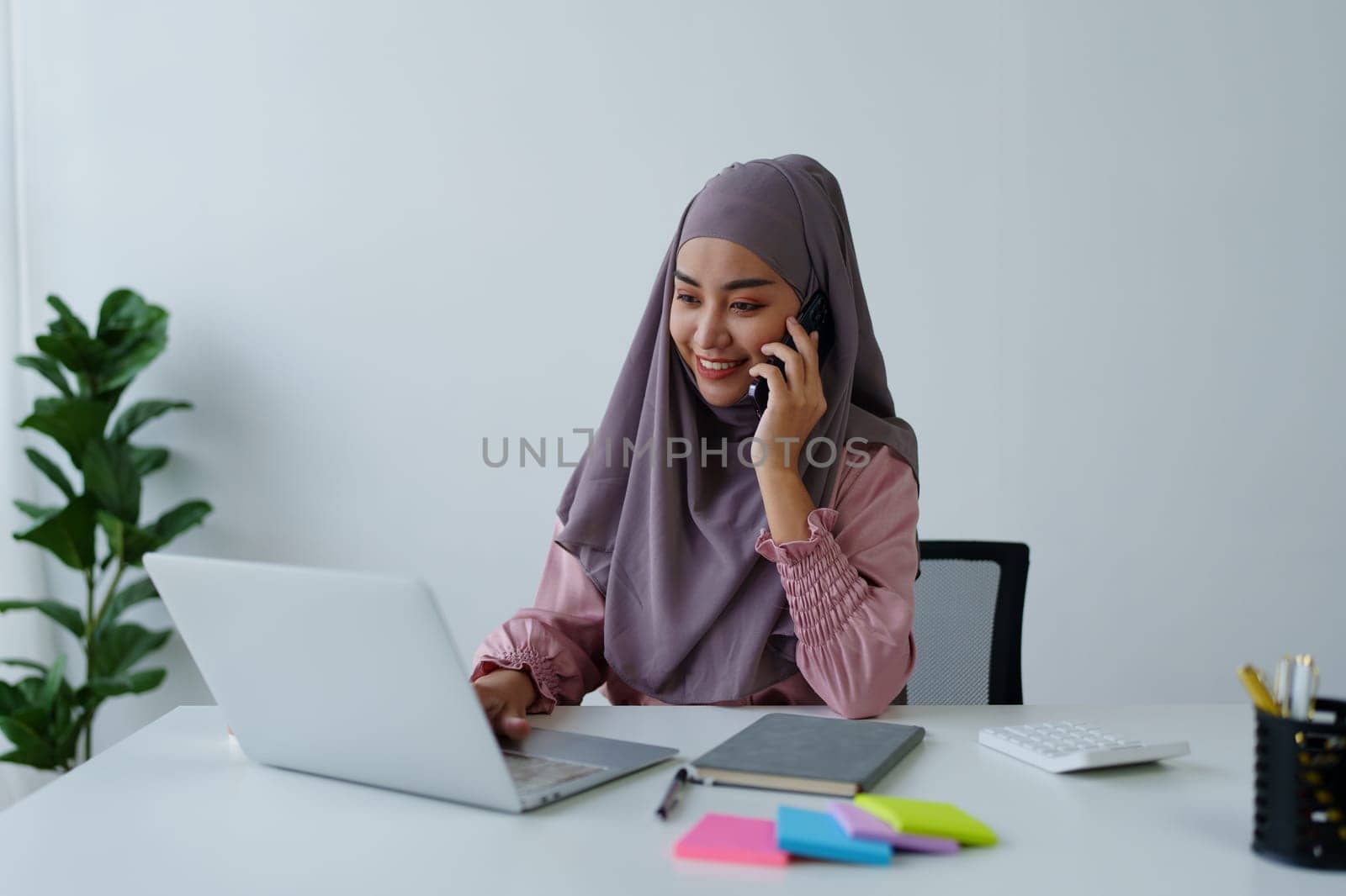 Muslim female employee Using the phone to talk to customers in the office