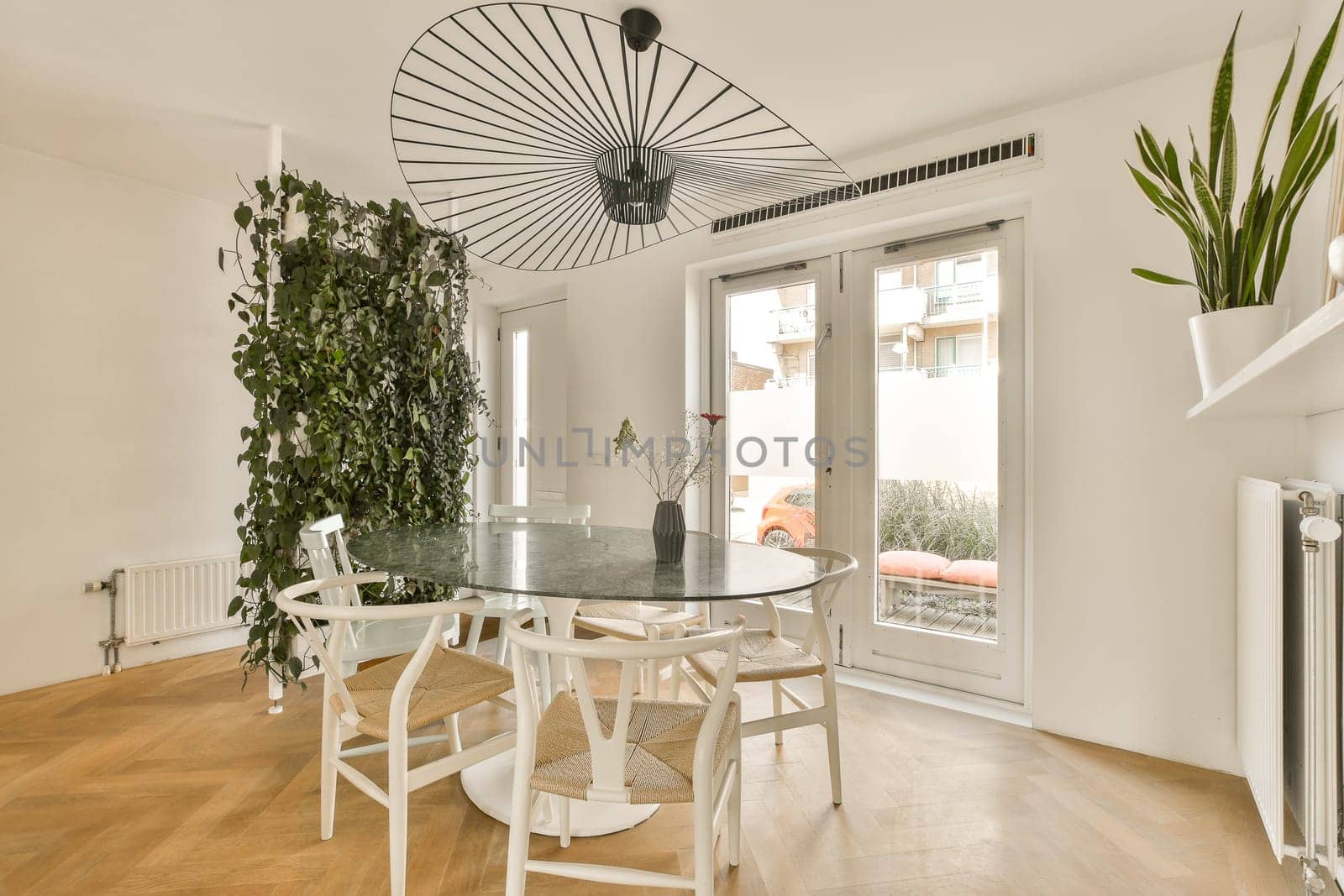 a dining table and chairs in a living room with an air plant on the wall next to the glass door