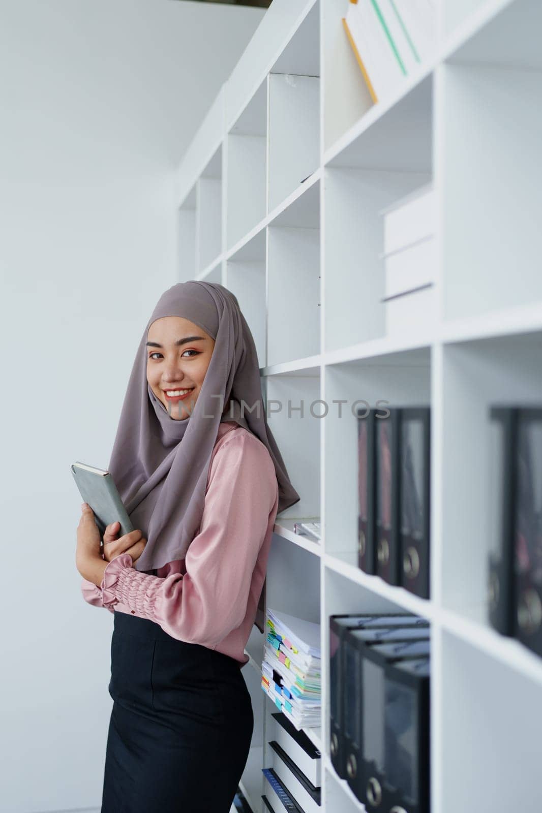 Muslim female employee Searching for documents in the office. by Manastrong