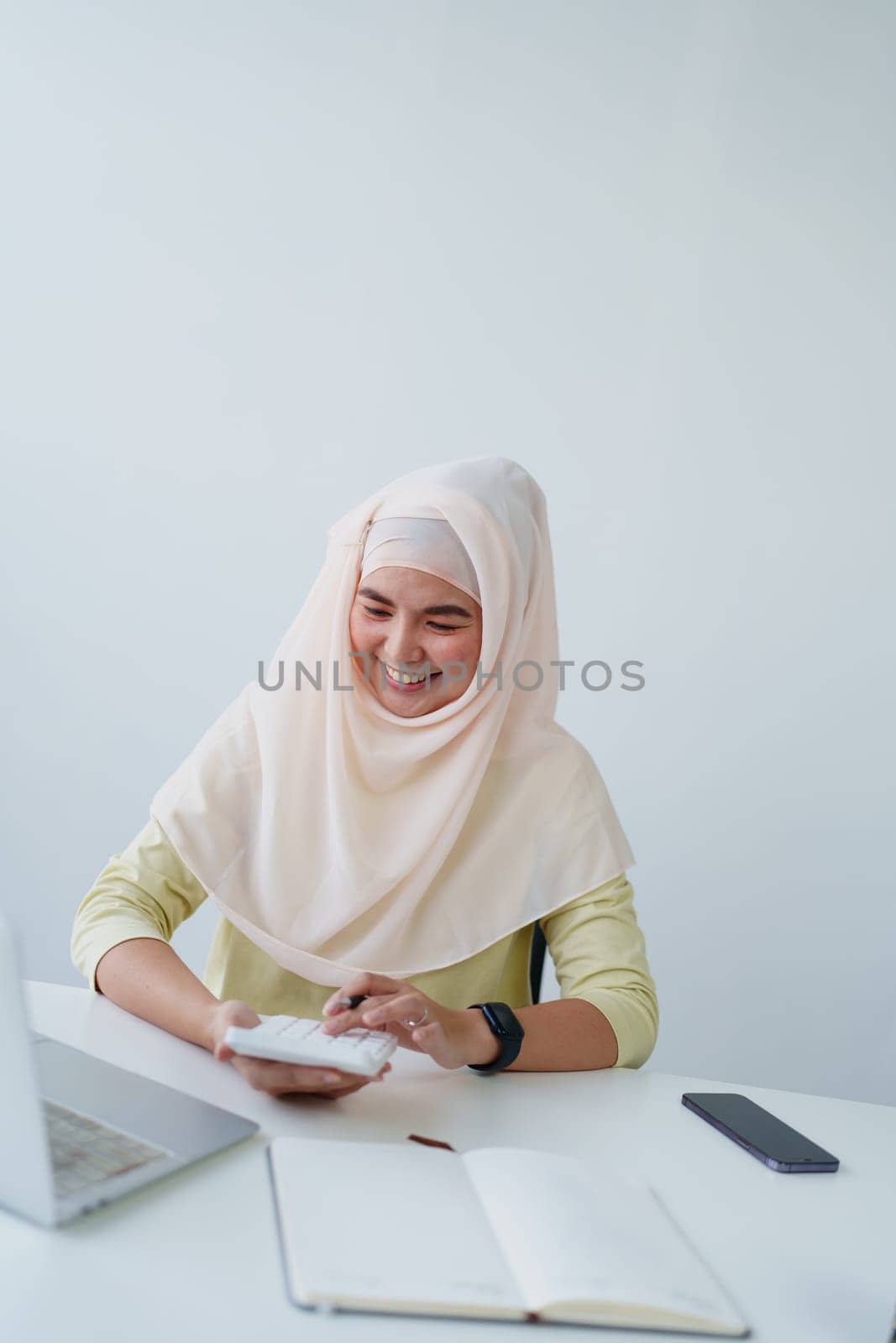 Muslim women use calculators, computers, and laptops to check their accounts at work