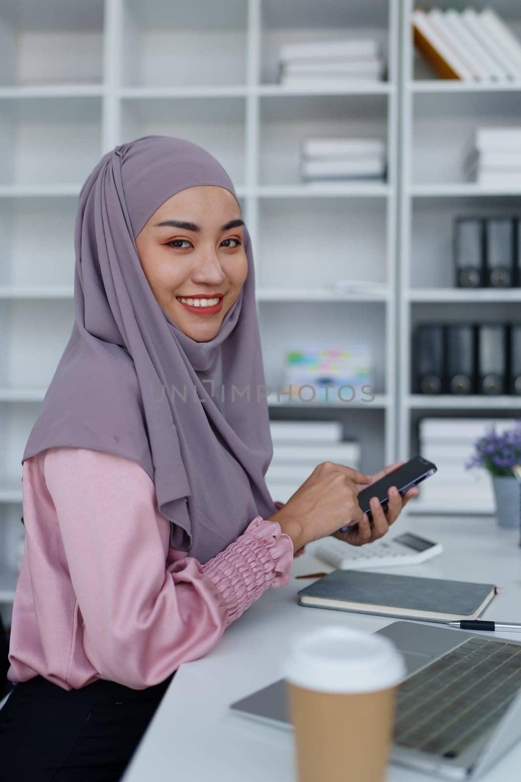 Muslim female employee Using the phone to talk to customers in the office