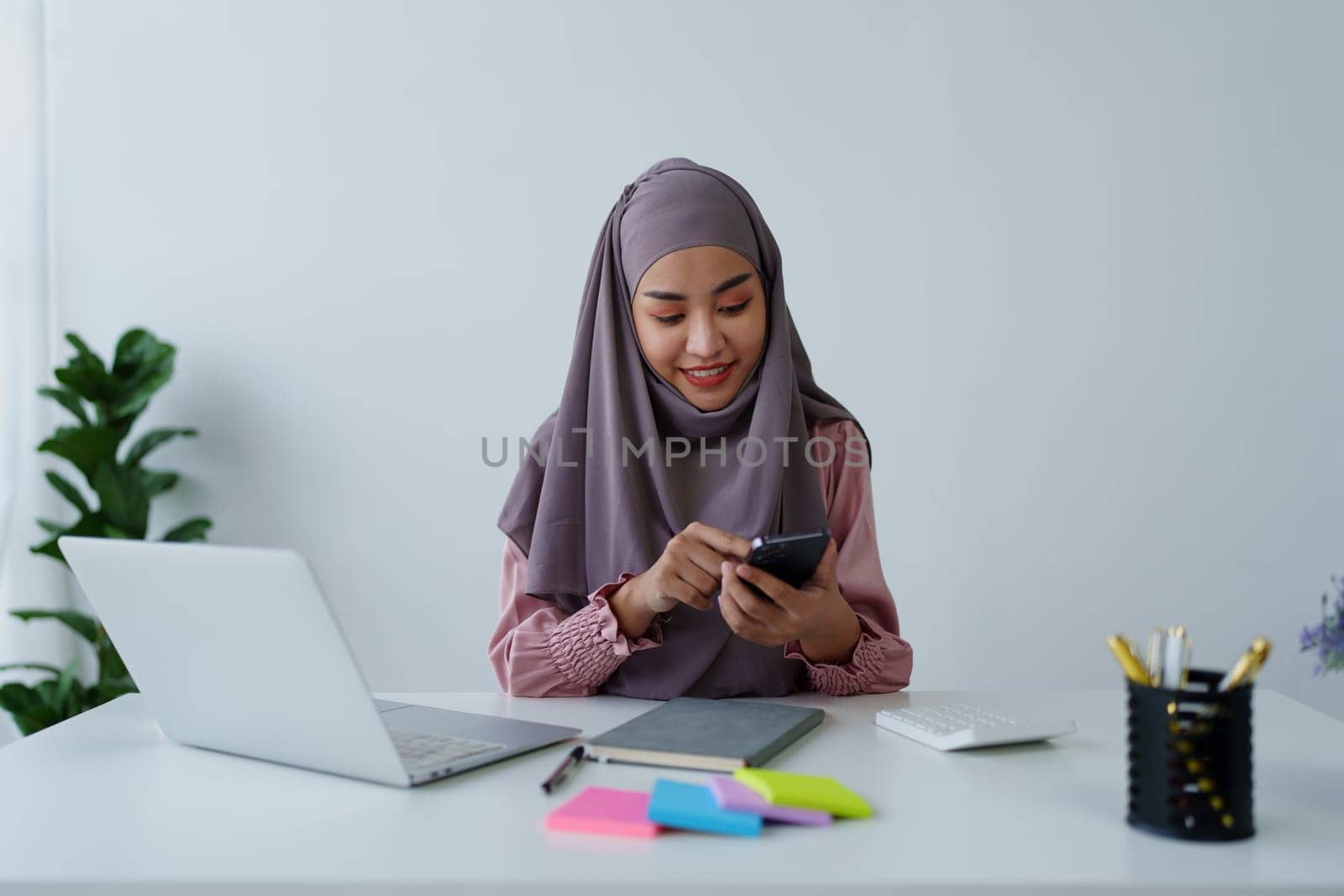 Muslim female employee Using the phone to talk to customers in the office. by Manastrong