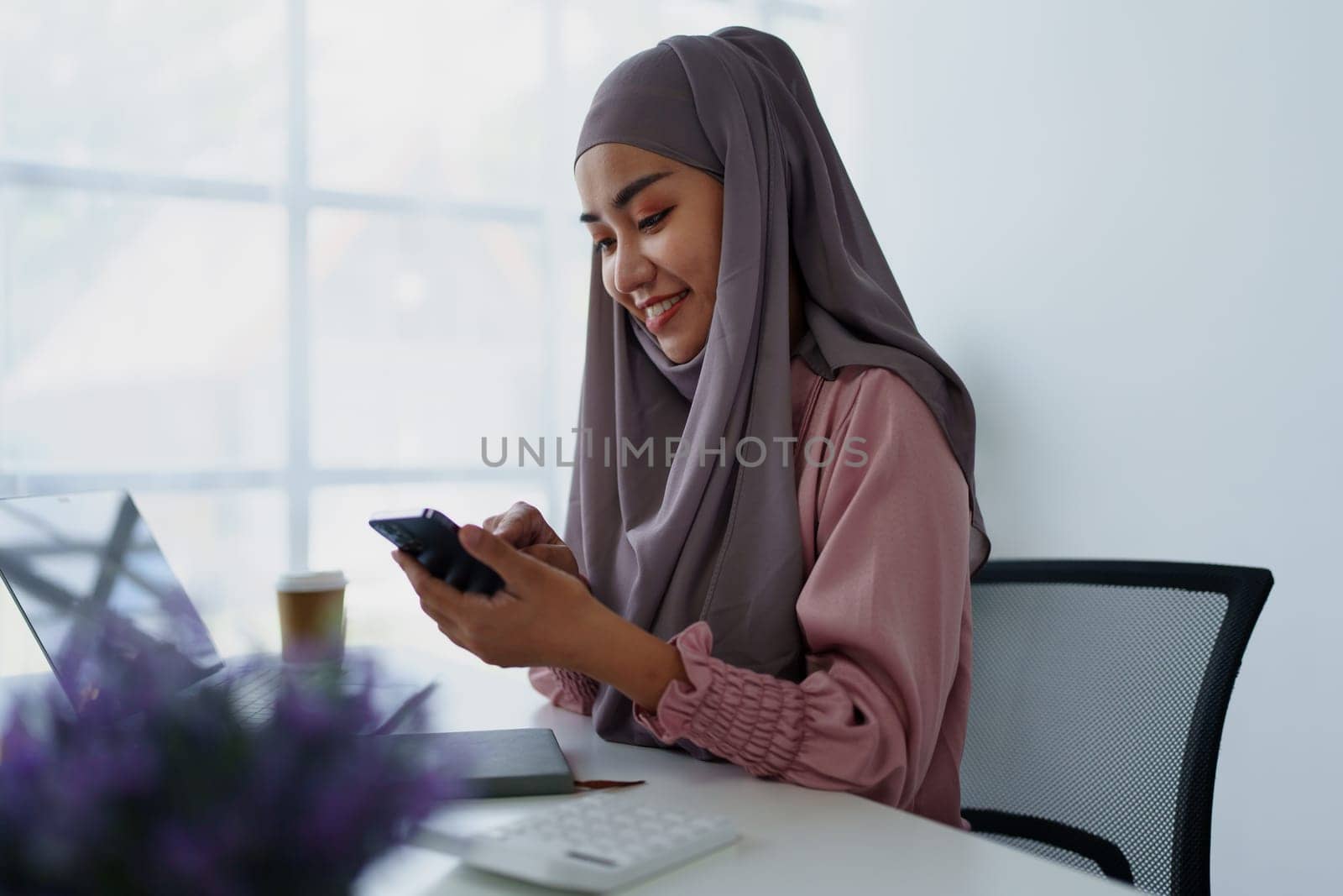 Muslim female employee Using the phone to talk to customers in the office. by Manastrong