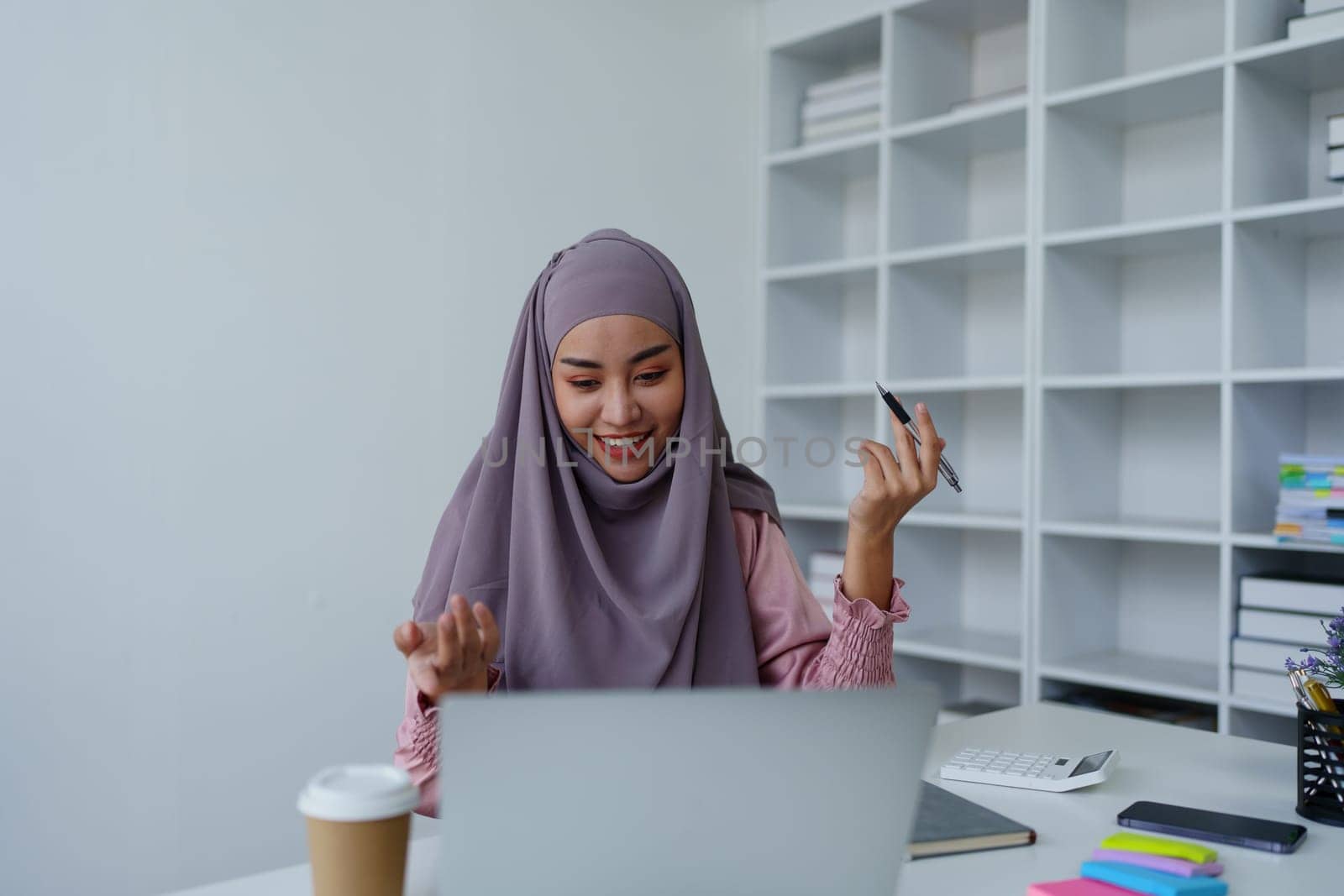 Muslim female employee Conferencing via computer during work. by Manastrong