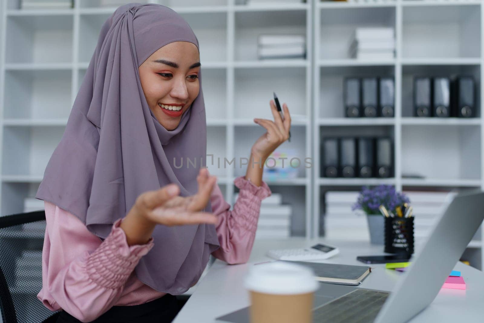Muslim female employee Conferencing via computer during work. by Manastrong
