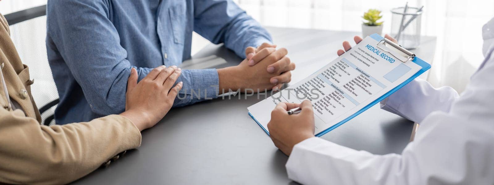 Doctor providing compassionate healthcare consultation while young couple patient holding hand, comfort each other after infertile report. Reproductive and medical fertility consulting. Neoteric