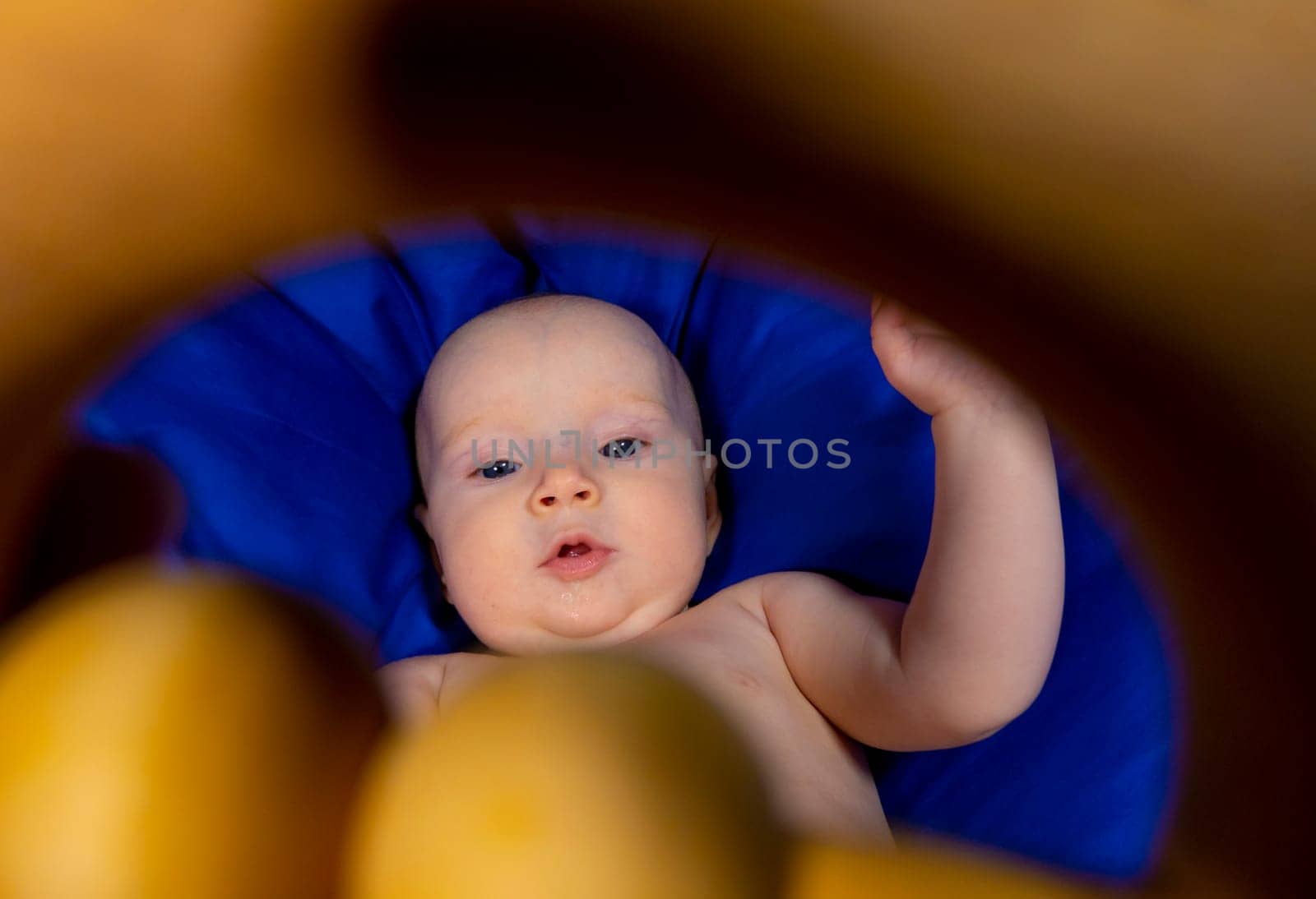 a baby in a tiger diaper on a blue background with a wooden rattle