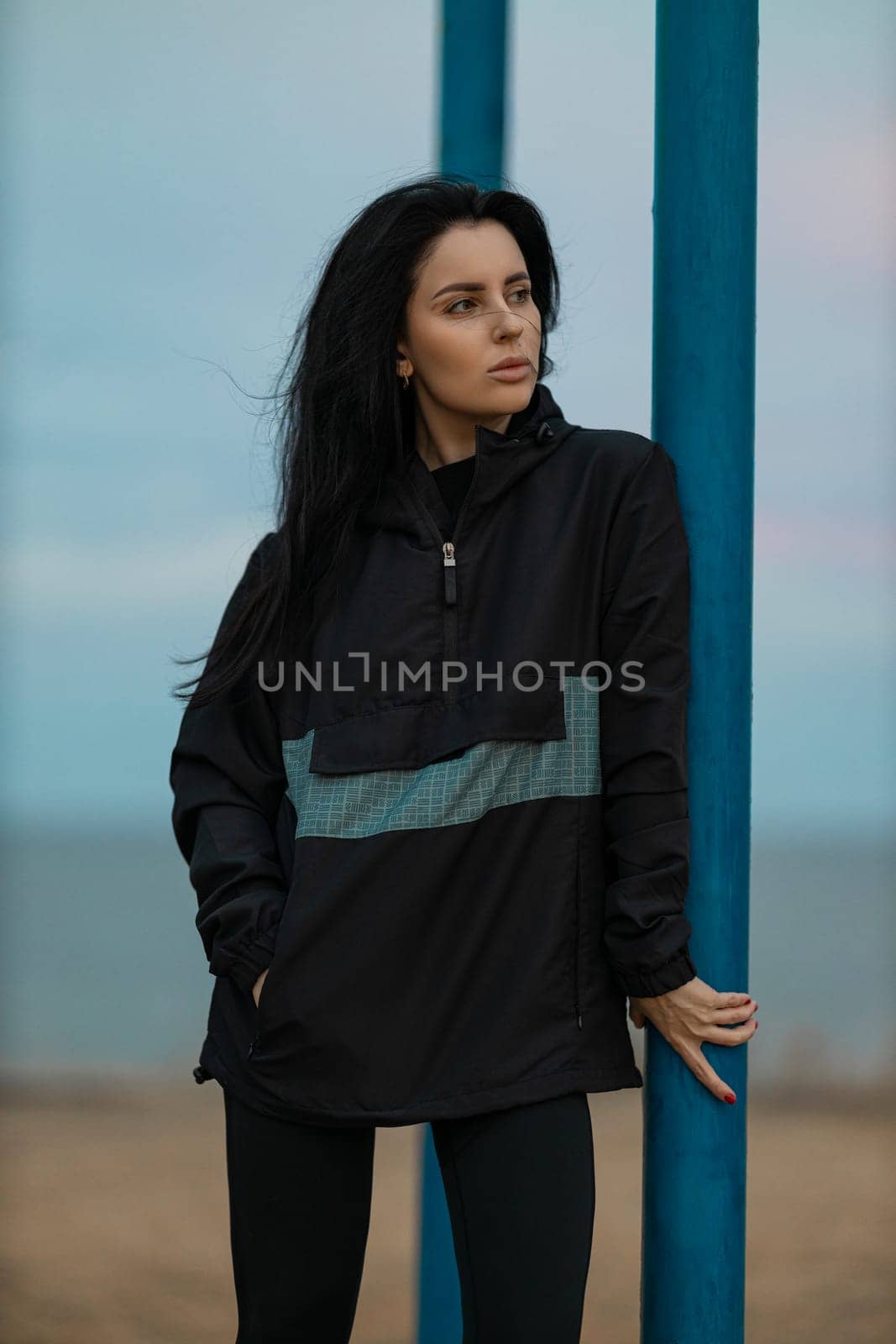 Fitness girl on outdoor sports ground in an anorak in windy weather by but_photo