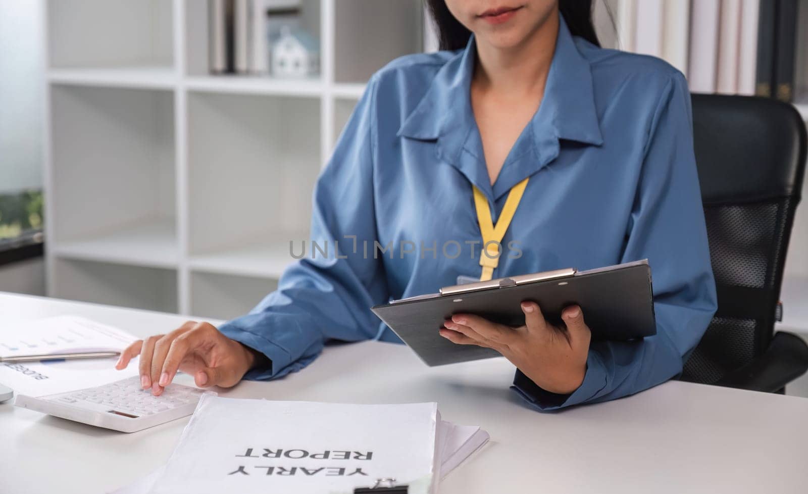 Businesswoman uses laptop and calculator to do finance, paperwork. Mathematics clipboard on table in office and business background, tax, accounting, statistics and analytical research concept..