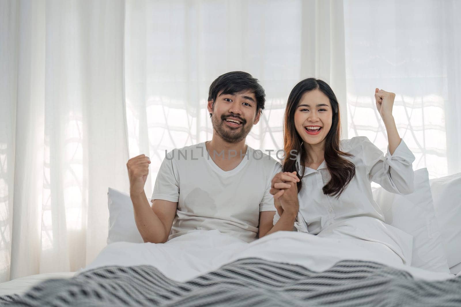 Love, happiness and a couple in bed on a beautiful morning at home. Wake up together brightly Woman and man relax in bedroom, romance, happiness by wichayada