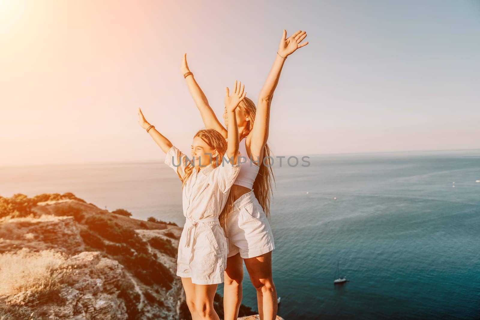 Sea family vacation together, happy mom and teenage daughter hugging and smiling together over sunset sea view. Beautiful woman with long hair relaxing with her child. Concept of happy friendly family. by panophotograph