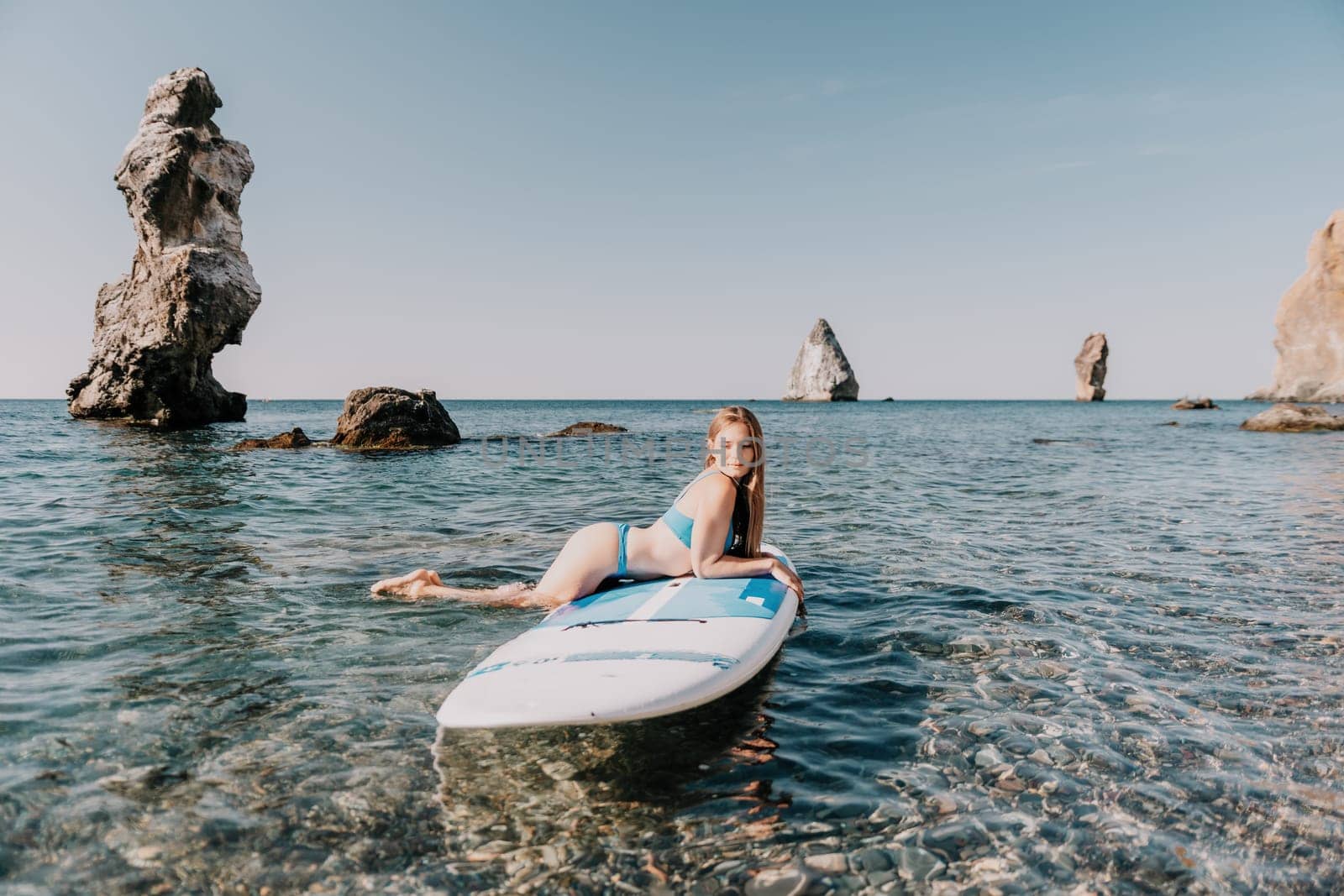 Close up shot of happy young caucasian woman looking at camera and smiling. Cute woman portrait in bikini posing on a volcanic rock high above the sea