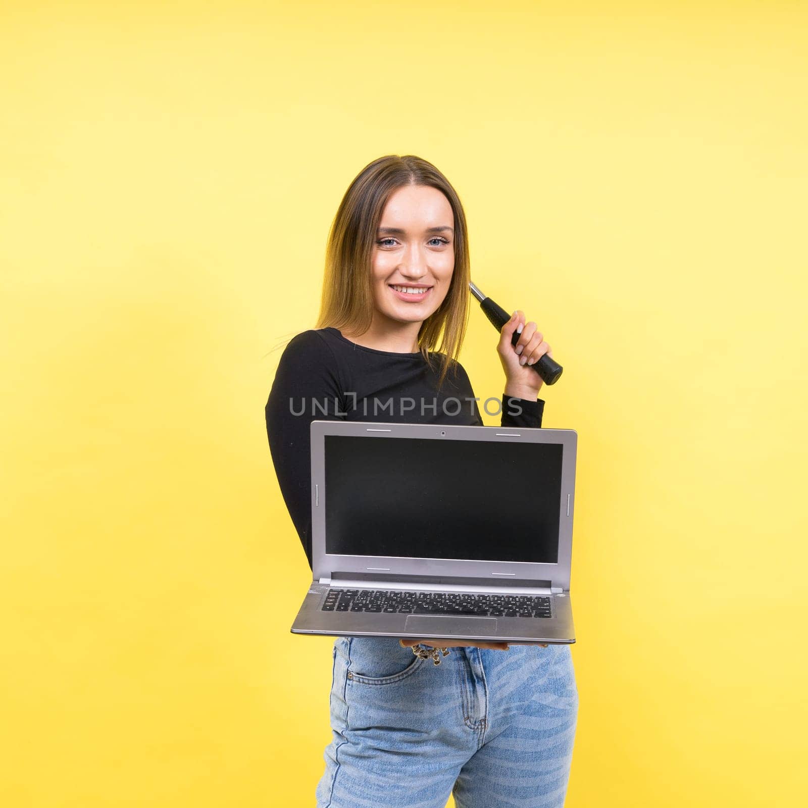 Laptop Repair. Female with hammer and laptop on yellow background by Zelenin