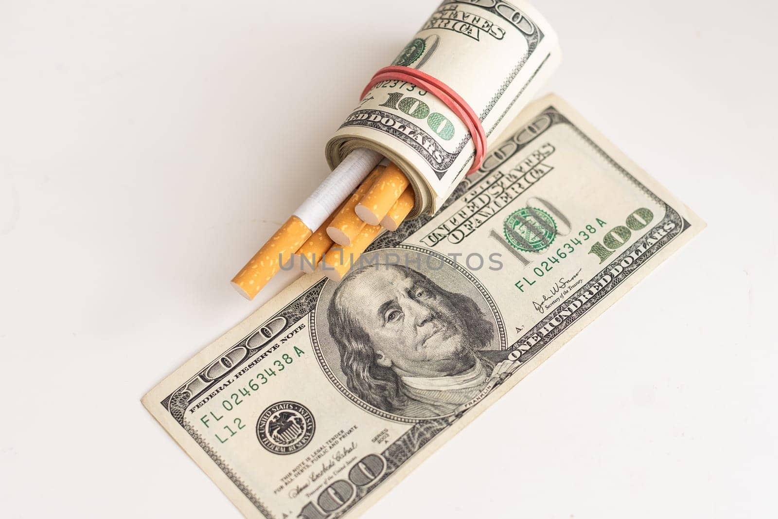 A roll of 100-dollar bills with cigarettes on a background. Concept of expensive cigarettes. by Andelov13