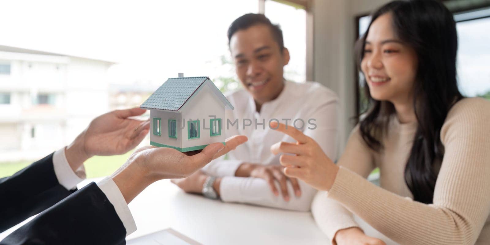Young married couple sitting at table listening to realtor, real estate agent, loan broker or mortgage advisor telling about options.