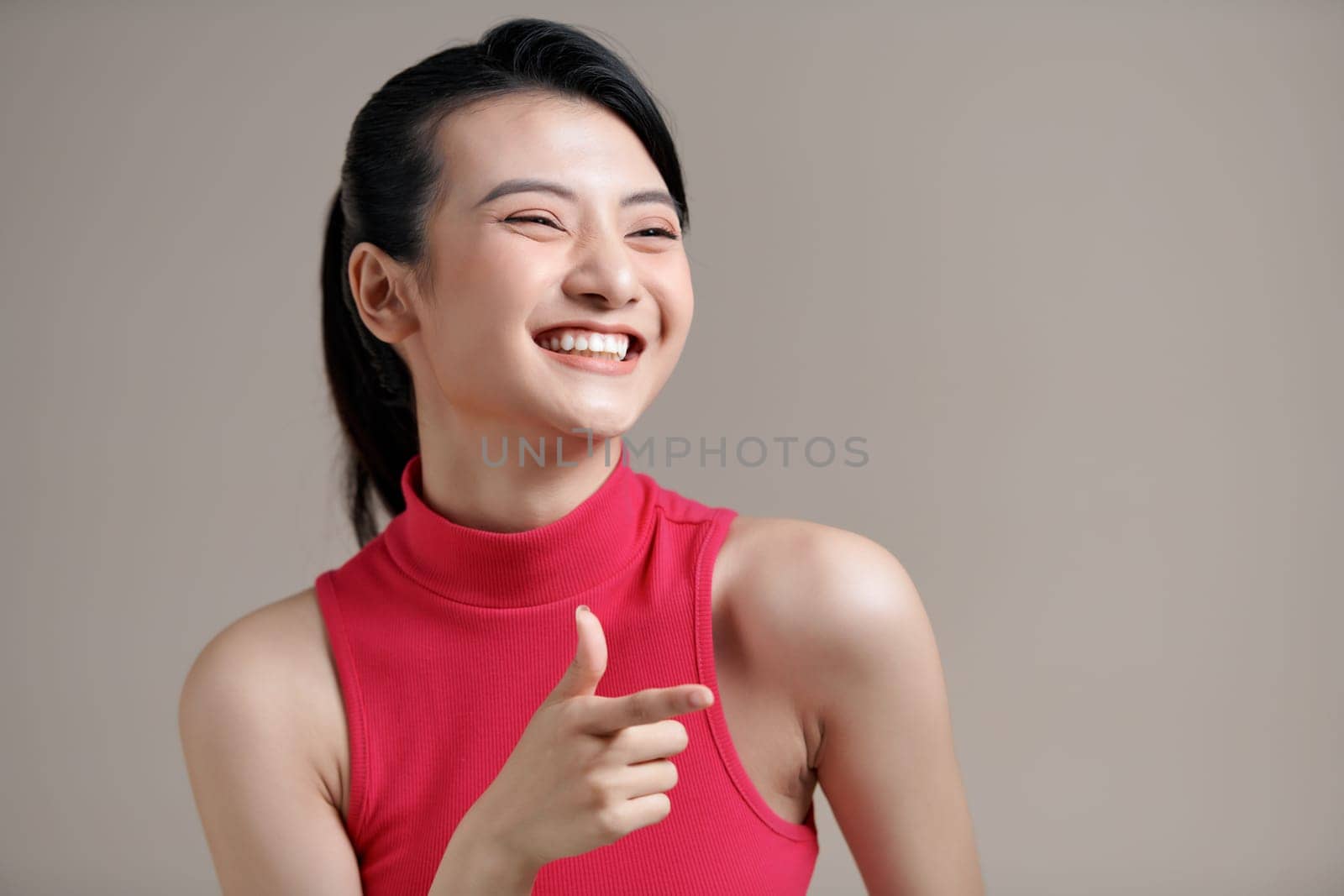 young smiling positive asian happy woman stand point index finger aside on workspace copy space