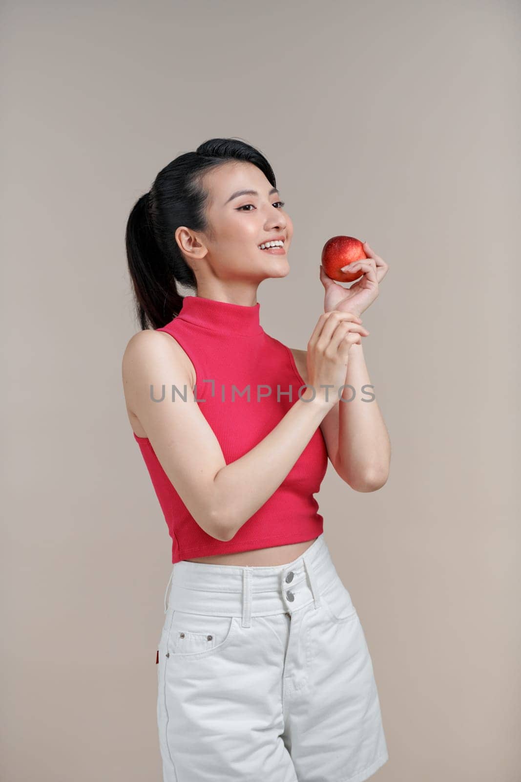 Woman with perfect smile holding apple on beige background