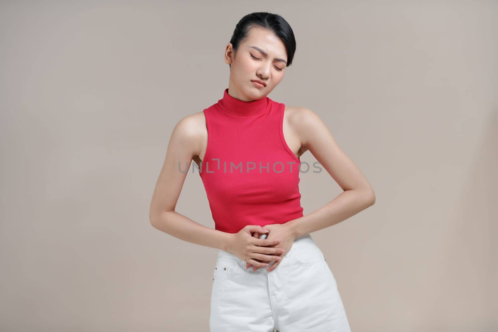 Asian woman suffering from stomach pain on beige background by makidotvn