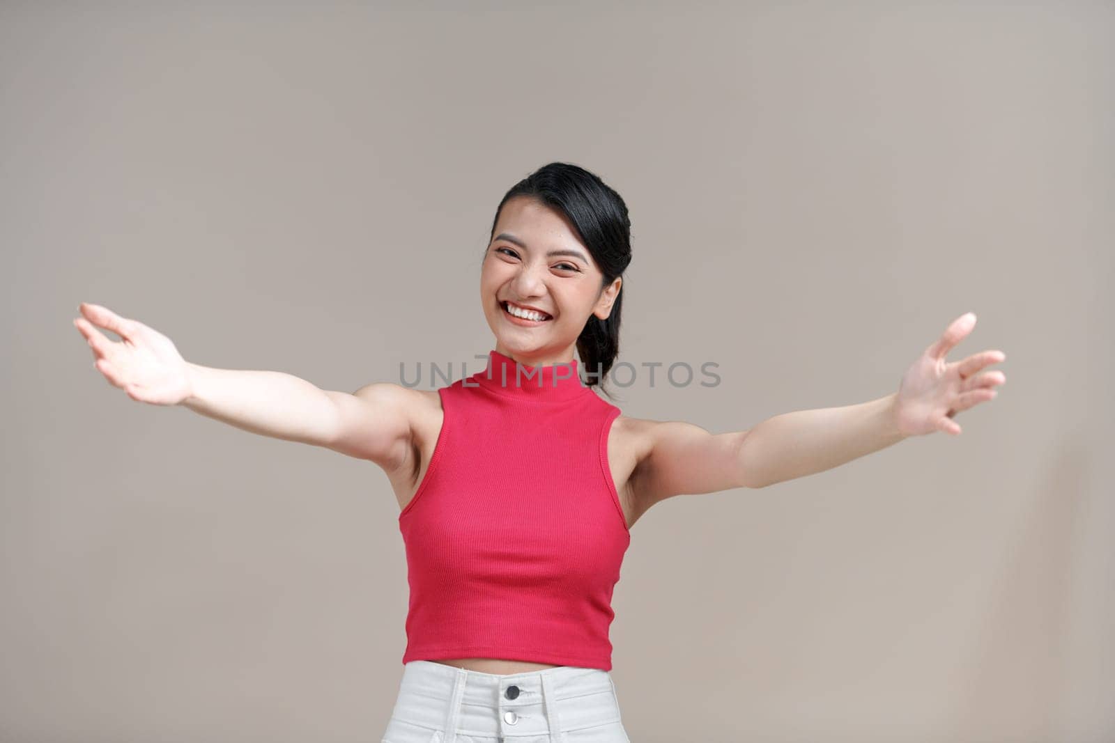 Asian woman wearing trendy clothes looking at the camera smiling with open arms for hug.  by makidotvn