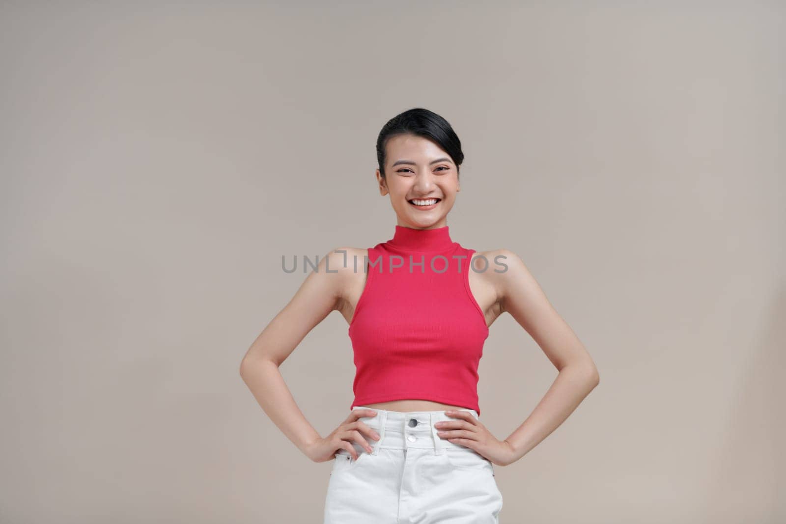 portrait of young smiling woman akimbo isolated on beige by makidotvn