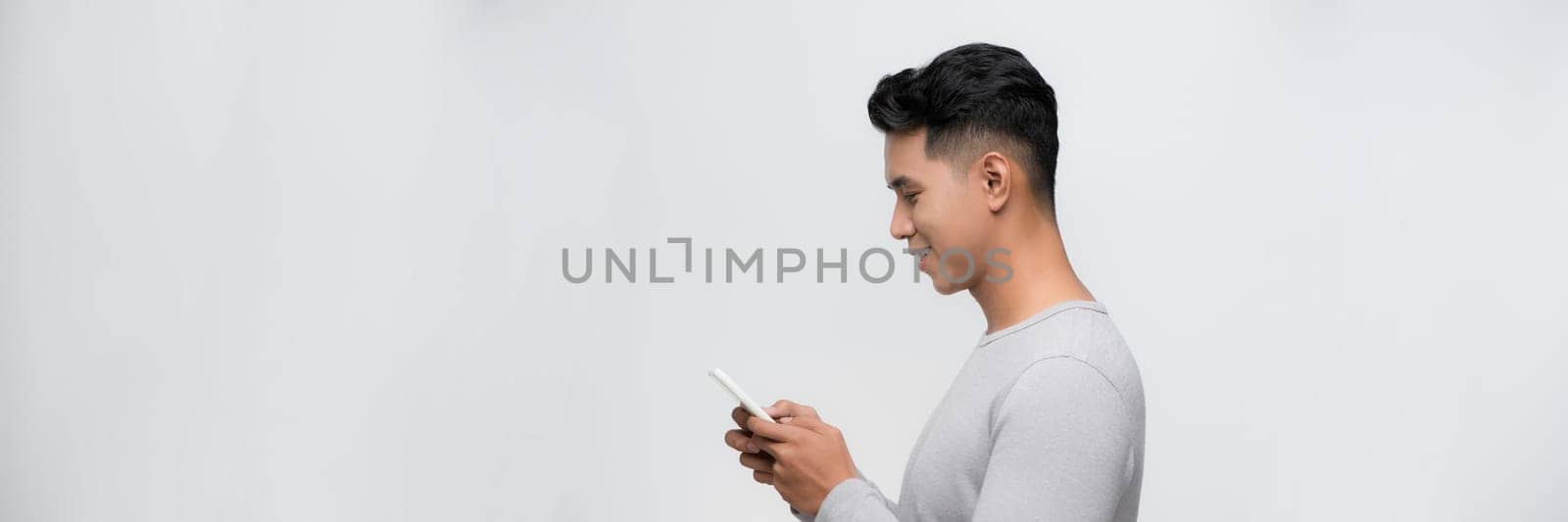 Image of smiling young man using mobile phone isolated by white background