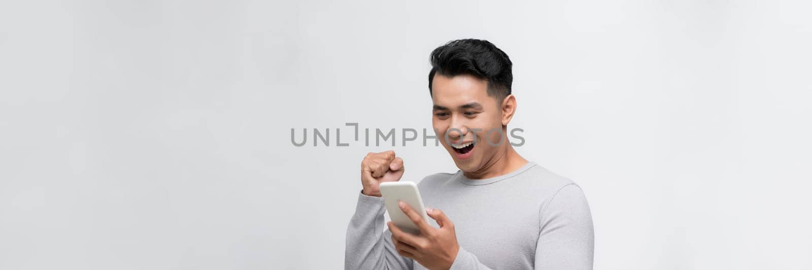 Happy winner! Young handsome man smiling holding tablet and playing games