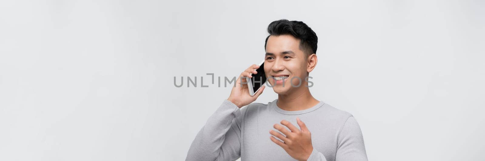 Young man isolated on white background keeping a conversation with the mobile phone with someone by makidotvn