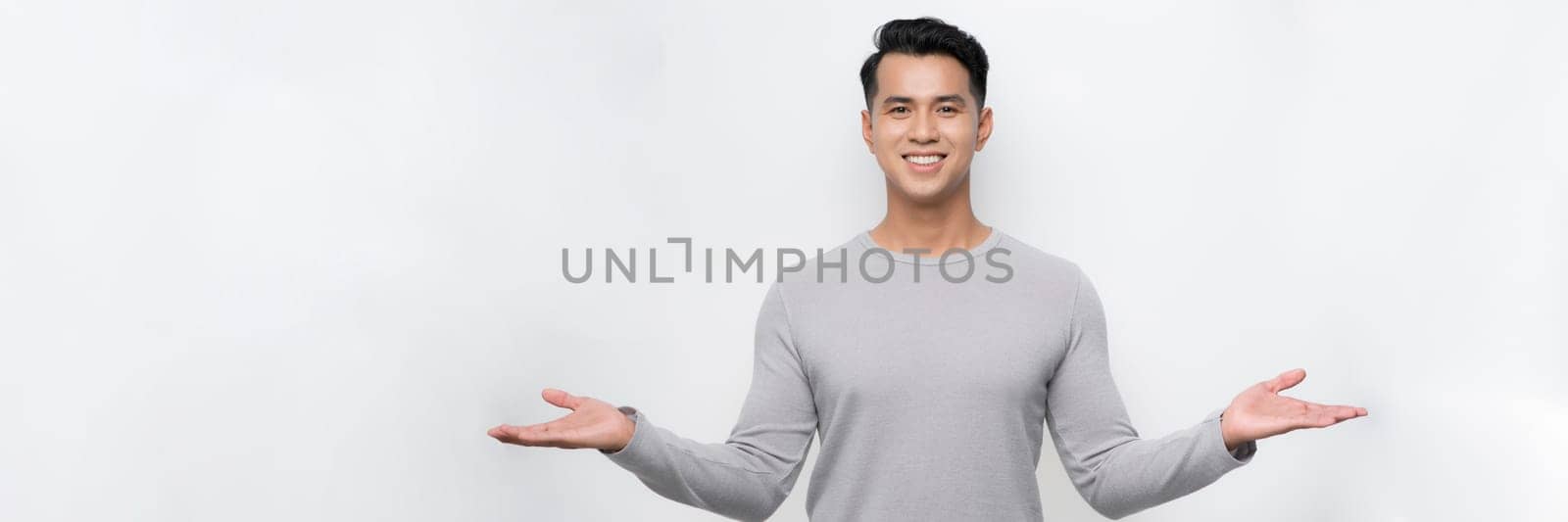 Attractive young Asian man smiling and welcoming heartily with arms open on banner