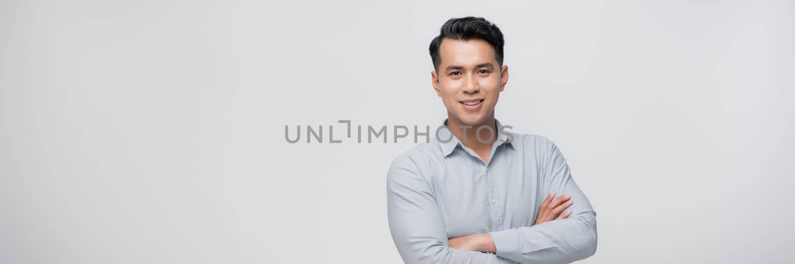 Positive young asian male looking away with smile while standing against white background by makidotvn