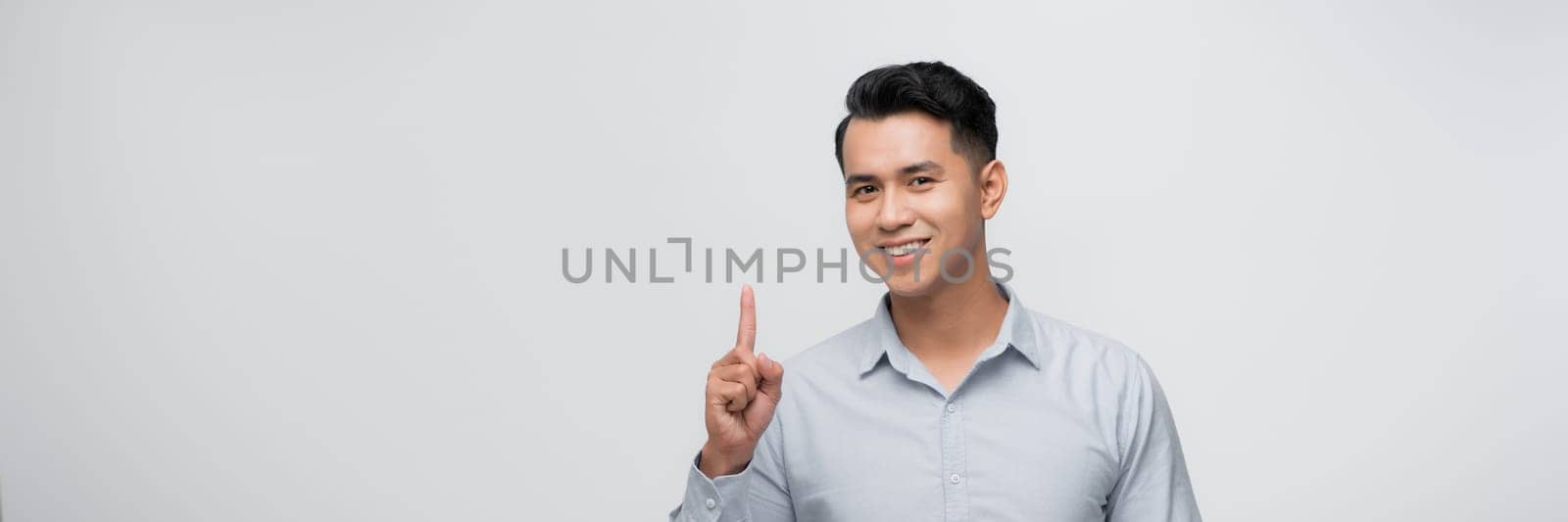 Attractive young man pointing up with his finger isolated on gray background by makidotvn