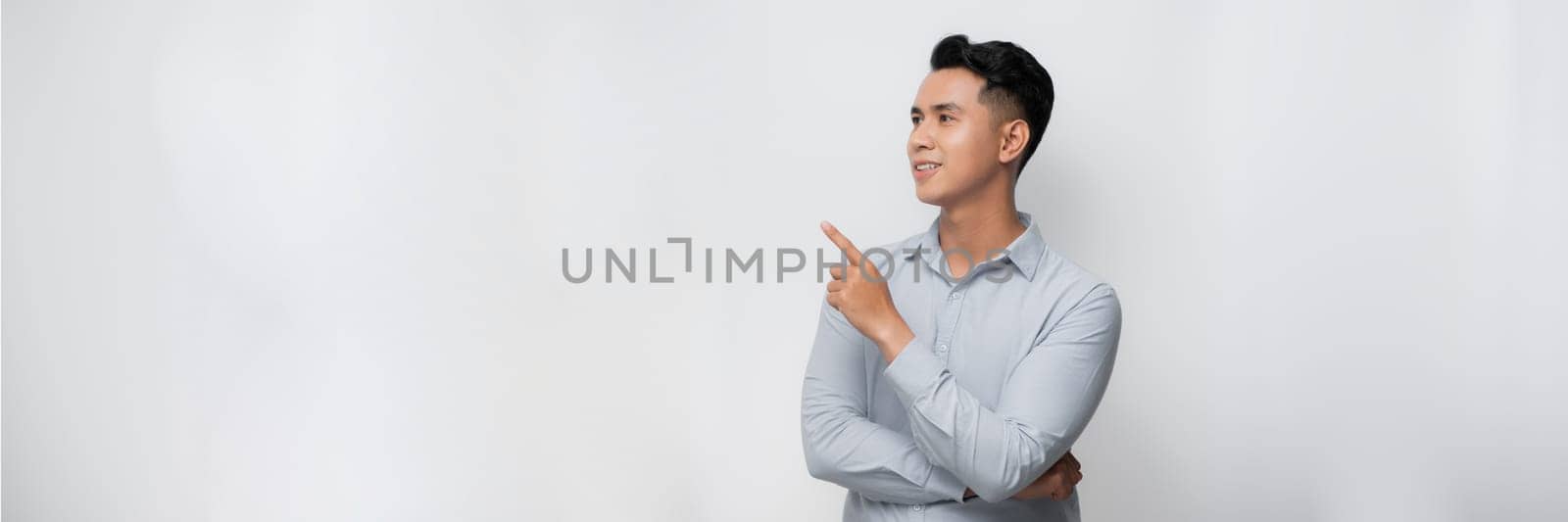 smiling young handsome Asian man pointing fingers in empty space aside