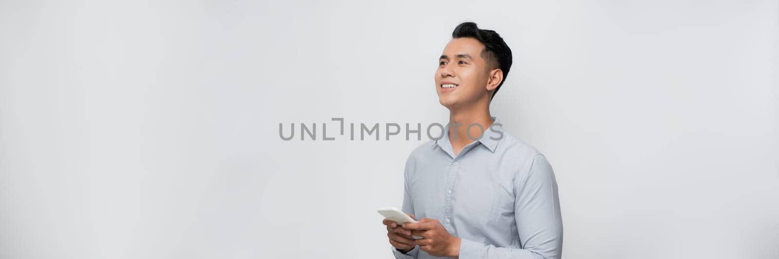 Young smiling handsome Asian man using mobile phone isolated on white background by makidotvn