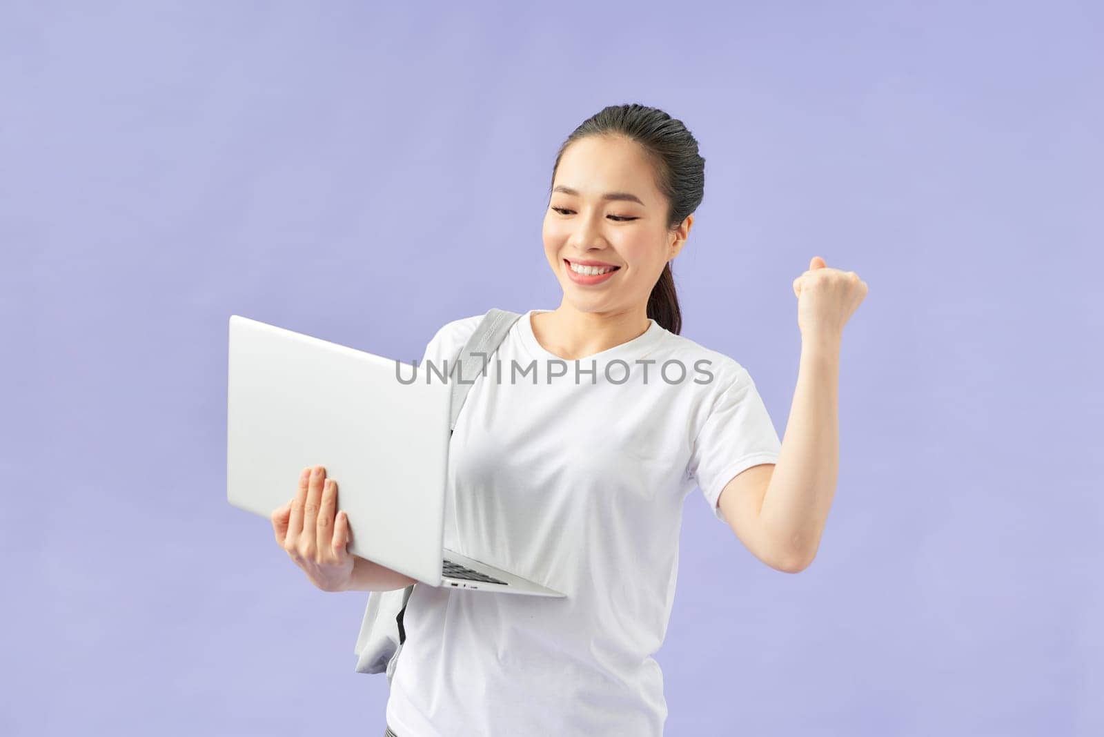 Young woman student backpack hold pc isolated on violet wall background studio portrait. by makidotvn