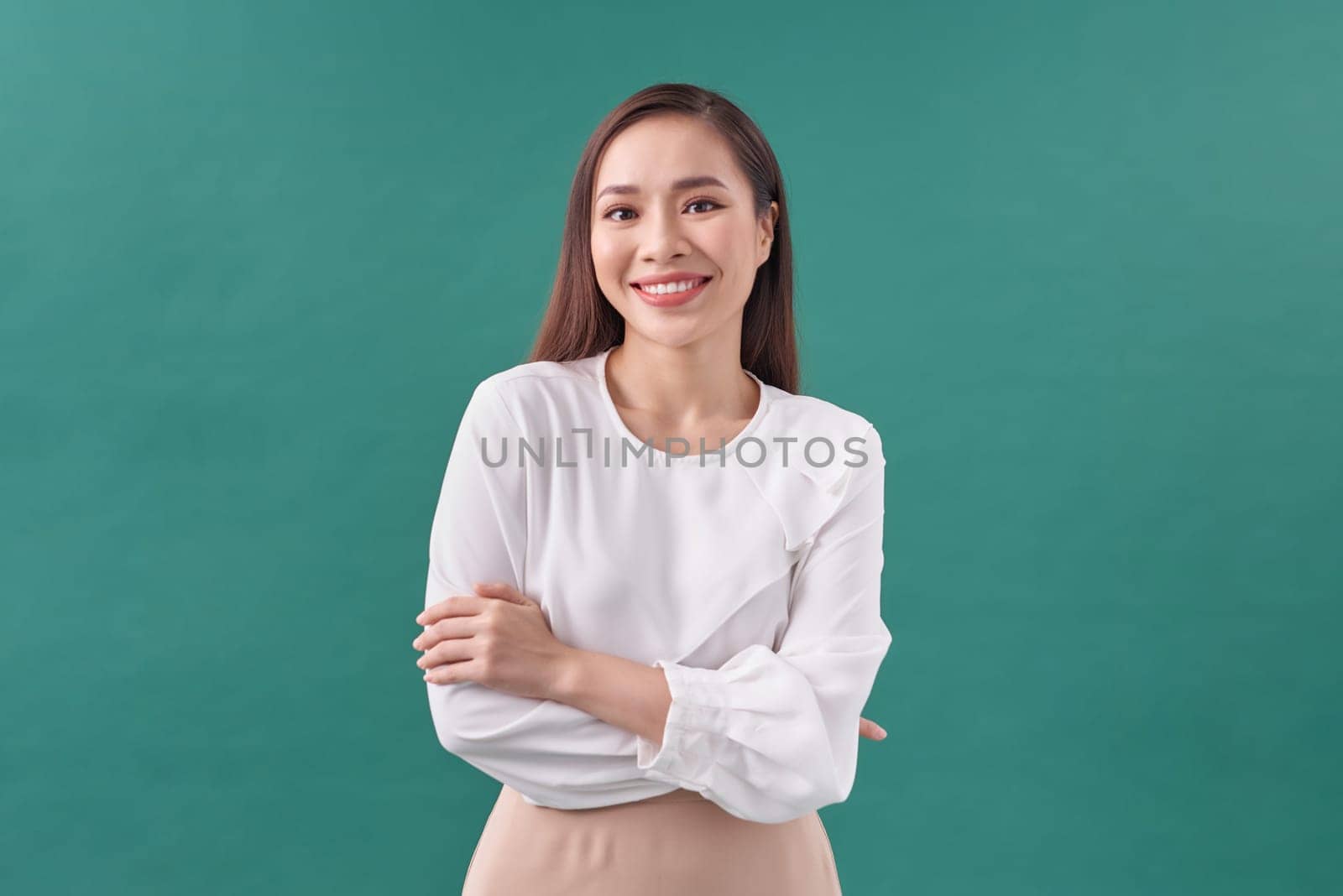 Young asian woman isolated on green background who feels confident, crossing arms with determination.