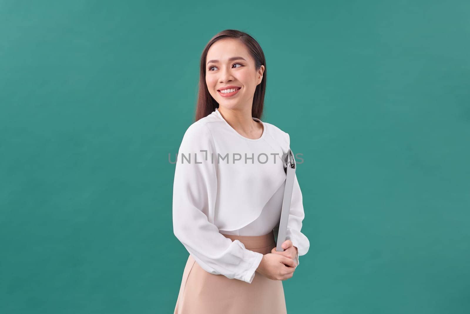 Portrait of a happy asian businesswoman holding clipboard isolated over green background