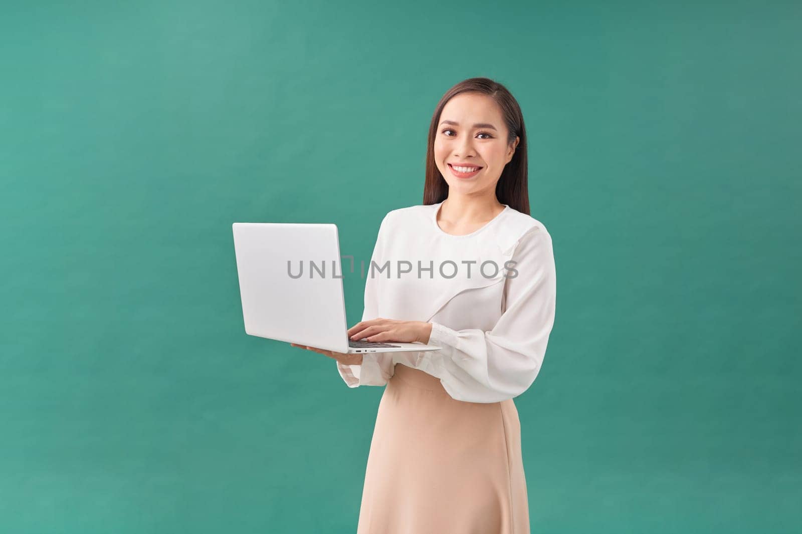 Young happy smiling woman in casual clothes holding laptop and sending email to her best friend by makidotvn