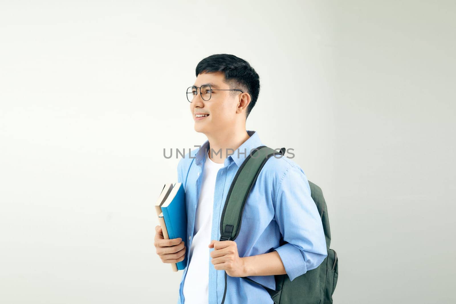 Young smiley student holding books carrying backpack, isolated on a white background. by makidotvn